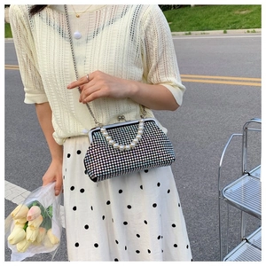 Rainbow rhinestone evening clutch with pearl handle and chain strap shown in outdoor setting