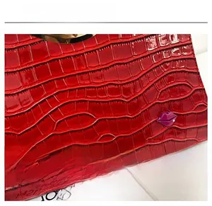 Détail d'un sac à main rouge à texture crocodile avec accessoire en forme de lèvres