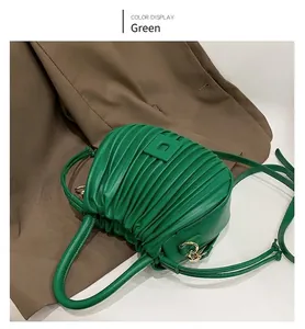 Detail of green pleated shoulder bag with square buckle and golden hardware accents