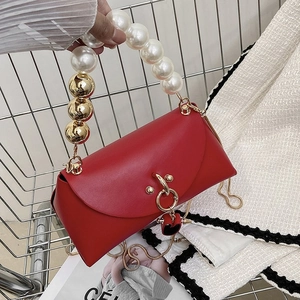 Detailed shot of red leather handbag with pearl handle and golden chain strap