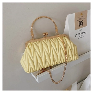 Detail of yellow pleated cloud bag with gold kiss-lock clasp and round metal handle