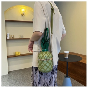 Détail du sac à bandoulière vert en forme d'ananas avec chaîne et clous dorés