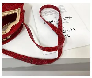 Détail du sac à main rouge en similicuir croco avec poignée dorée en forme de lèvres