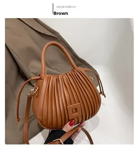 Detailed view of brown pleated cloud bucket bag with matte leather finish and side drawstring