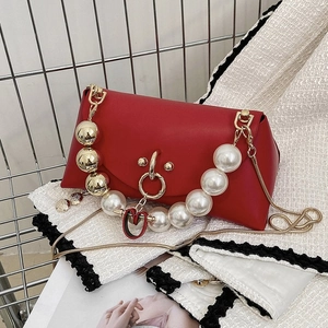 Detail of red leather crossbody bag featuring pearl handle and golden chain strap