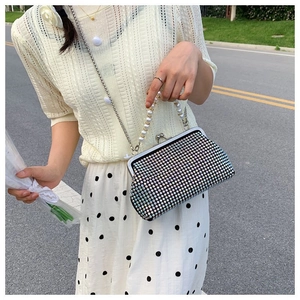 Detail of iridescent rhinestone shell bag with pearl handle and metal chain strap