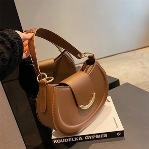 Close-up of brown leather saddle bag with golden half-moon buckle and stylish wide strap