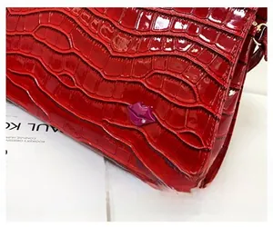 Détail du sac en cuir verni rouge à motif crocodile avec décoration lèvres en strass