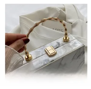 Detail of marble pattern box bag with gold bamboo handle and metal lock clasp