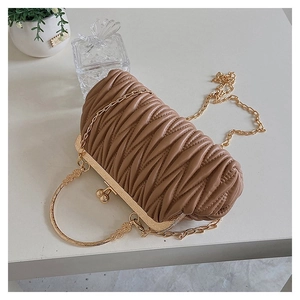 Detail of a brown ruched leather clutch with gold metal handle and chain on white surface