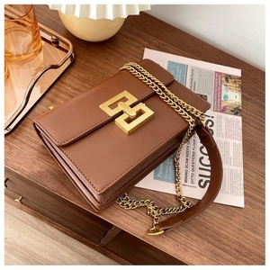 Close-up of vintage brown leather bag with golden H-shaped clasp and chain strap