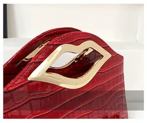 Vue détaillée du cuir rouge à motif crocodile avec poignée dorée en forme de lèvres