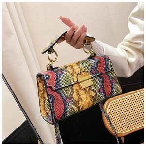 Detail of colorful snakeskin texture and gold metal buckle on a crossbody handbag