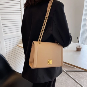 Détail du sac bandoulière beige avec chaîne dorée et fermoir rotatif en similicuir texturé