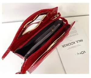 Détail du sac cabas rouge gaufré croco avec deux compartiments et poignées en métal doré
