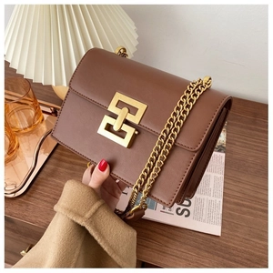 Detailed shot of brown faux leather flap bag with gold interlocking buckle and chain strap