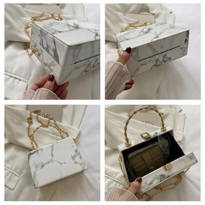 Detailed view of white marble texture box bag with gold bamboo handle and chain strap