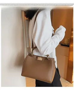 Borsa a tracolla marrone scuro con trama litchi e chiusura dorata indossata da modella