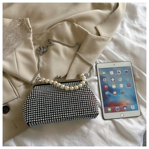 Detail of luxury rhinestone shell bag featuring pearl handle and silver metal chain strap