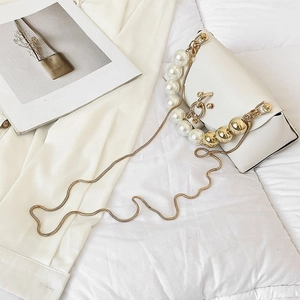Detail of white PU leather crossbody bag featuring pearl handle and gold snake chain