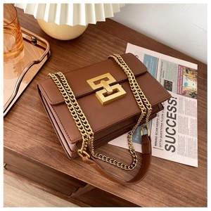 Detail of caramel brown retro flap bag with gold geometric lock and chain strap