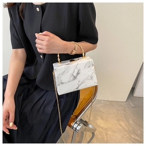 Detail of marble pattern box bag with gold wavy handle and metallic lock closure