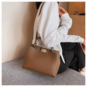 Dettaglio ravvicinato della borsa in pelle marrone con texture litchi e chiusura oro