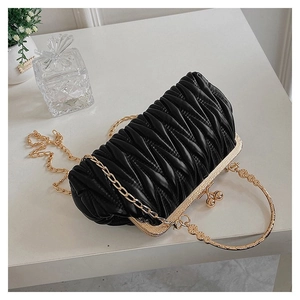 Detail of black matelassé handbag with gold frame, spherical clasp and metal chain strap