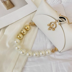 Detail of white PU leather handbag featuring a golden heart buckle and pearl chain strap
