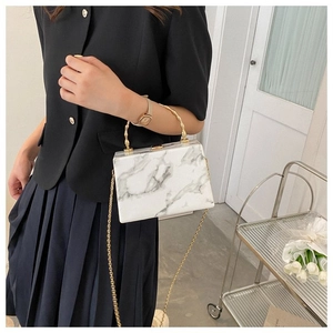Detail of marble pattern box bag with gold bamboo handle and metallic chain strap