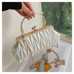 Detail of white quilted cloud bag featuring retro gold metal handle and chain strap