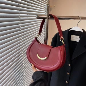 Retro burgundy half-moon shoulder bag with gold buckle in a minimalist fashion scene