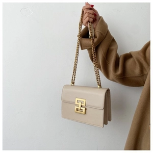 Detailed view of beige leather bag with interlocking gold clasp and elegant chain strap