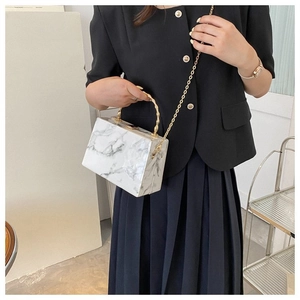 Detail of white marble textured acrylic box bag with gold bamboo metal handle