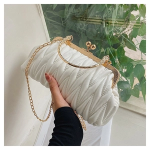 Detail of white quilted handbag with golden spherical clasp and chain strap