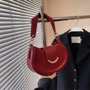Detail view of red crescent saddle bag with gold metal buckle and wide strap
