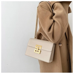 Detail of cream beige crossbody bag with gold geometric clasp on camel wool coat
