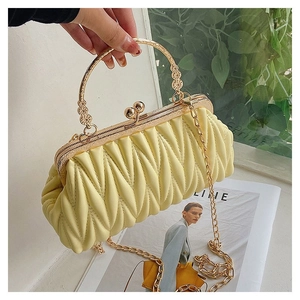 Detailed view of pale yellow pleated clutch with gold metal ring handle and chain strap