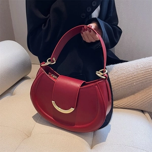Detailed close-up of red leather saddle bag with luxury gold buckle and ring accents