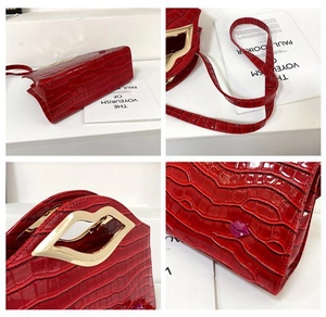 Détails d'un sac à main rouge motif crocodile avec poignée dorée en forme de lèvres
