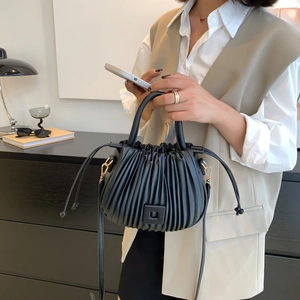 Elegant black pleated bucket bag with drawstring closure and square buckle accessory