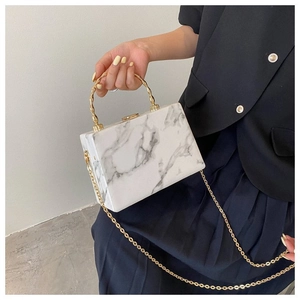 Close-up of white marble pattern crossbody bag with golden bamboo metal handle