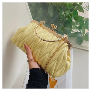 Close-up of a pale yellow pleated handbag with gold round handle and chain strap