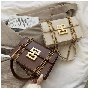 Detail of cream and brown crossbody bags with gold geometric buckles and chain straps
