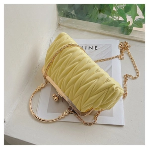 Macro shot of yellow quilted cloud bag with gold ring handle and metal chain strap