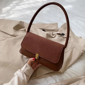 Minimalist brown leather and suede shoulder bag with vintage gold clasp on beige fabric