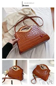 Détail du sac à bandoulière marron motif crocodile avec poignée dorée en forme de lèvres