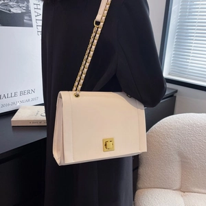 Sac à bandoulière blanc chic avec chaîne dorée et cuir mat porté par le mannequin