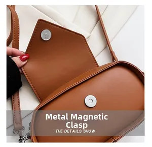 Detailed view of the silver magnetic clasp and stitching on the brown leather bag