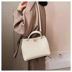 Dettaglio borsa in pelle bianco crema con chiusura a scatto dorata e manico superiore